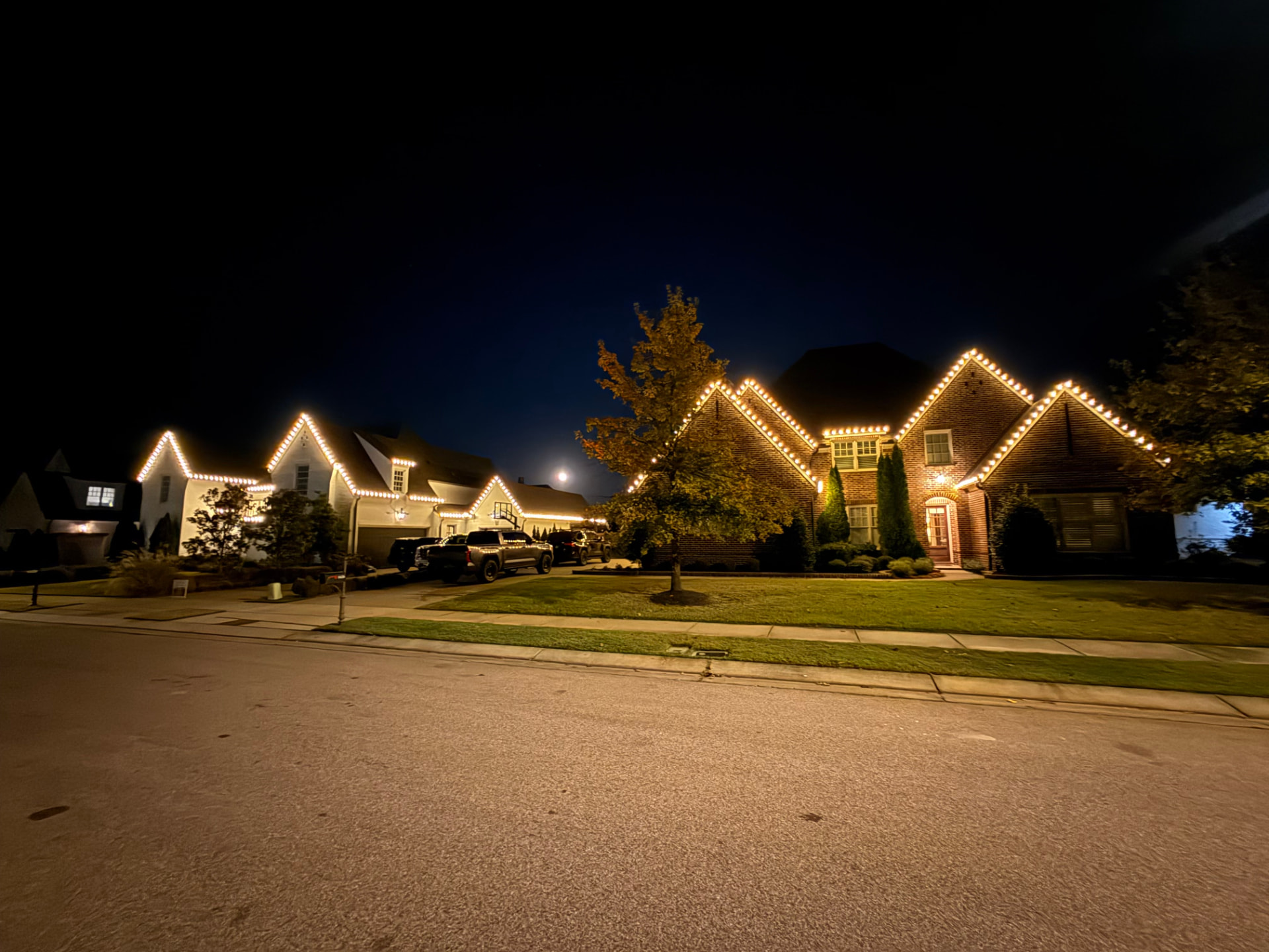 Multiple neighborhood homes with coordinated warm white Christmas lighting