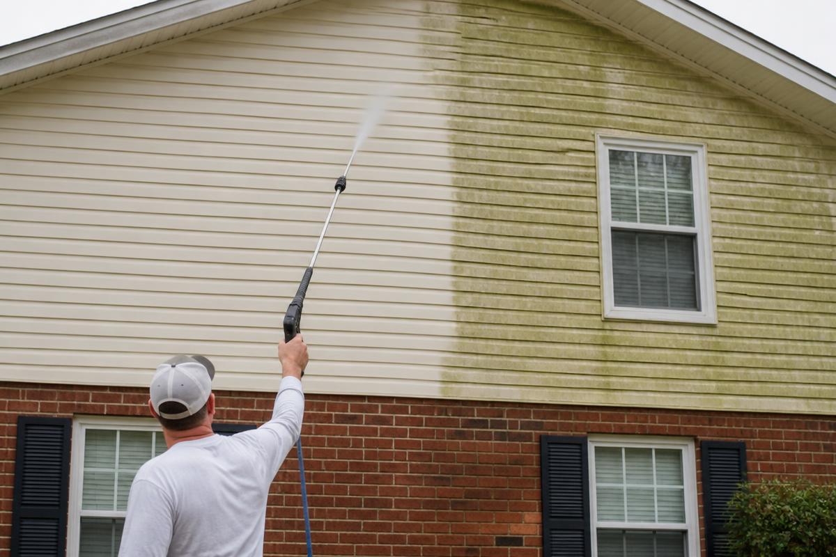 Soft washing green organic growth off vinyl siding on an Alabama home